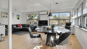 Un soggiorno moderno con zona pranzo, ampie finestre e televisore a schermo piatto.