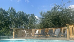 Un área de piscina con sillones de descanso y una terraza de madera.
