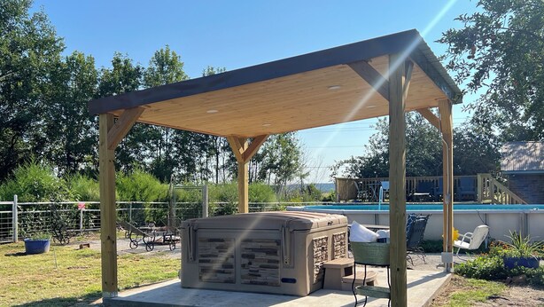 Un espacio de estar al aire libre cubierto, con una piscina al fondo.