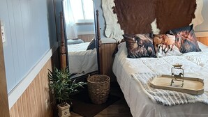 Un dormitorio con un espejo grande, un ventilador de techo y una cama con almohadones decorativos.