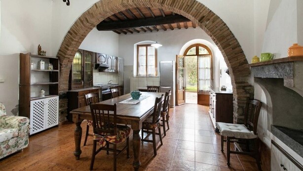 A rustic kitchen with an arched stone ceiling, wooden furniture, and a large dining table. - Maison Antoinette - Violet (Toscana)