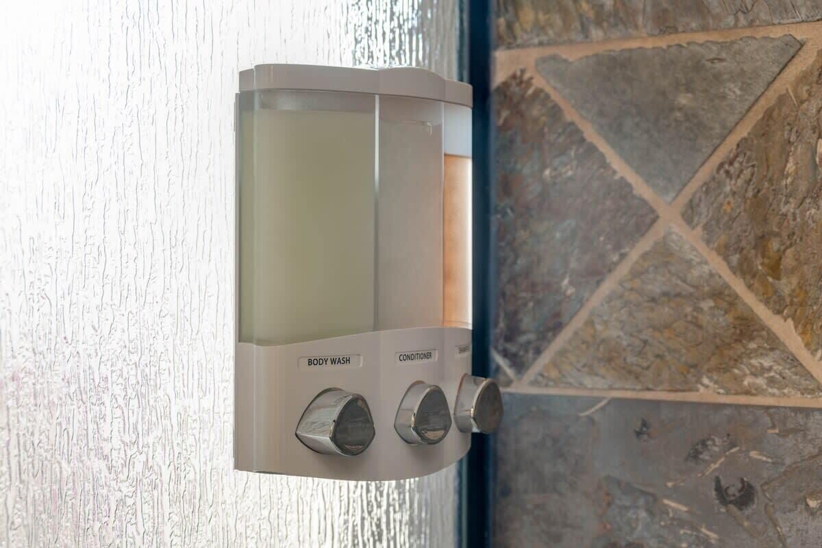 A wall-mounted shower with a control panel labeled "BODY WASH" and "CONDITIONER."