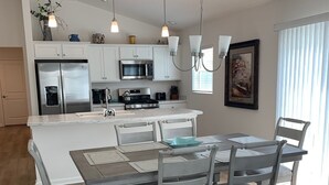 Une cuisine moderne avec des meubles blancs, des appareils en acier inoxydable et un îlot central.