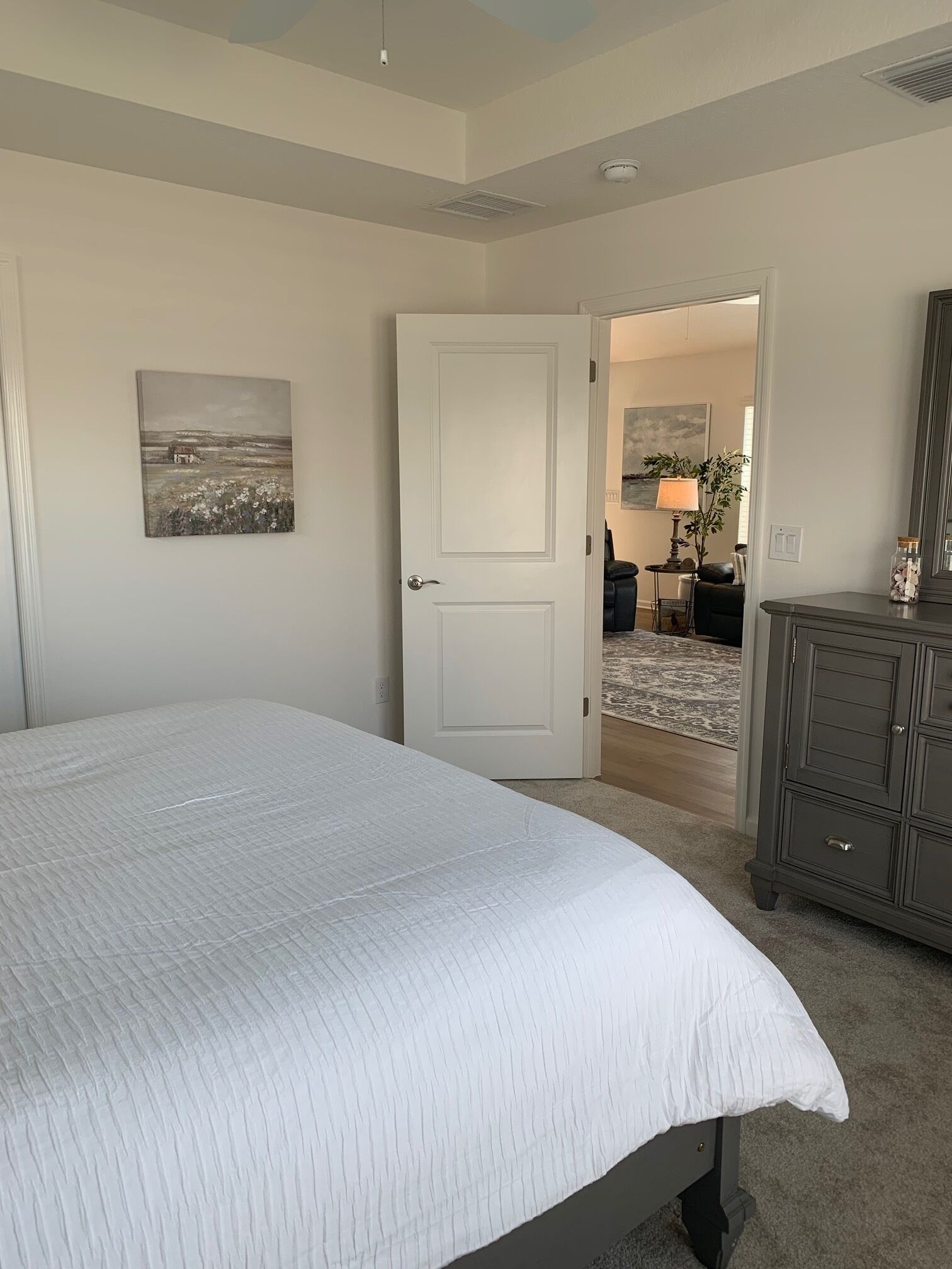 Ein Schlafzimmer mit einem großen Bett, einer Tür zu einem anderen Raum, einem Schminktisch und einem Bild an der Wand.