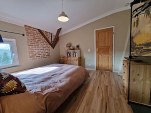 Quarto com cama, penteadeira de madeira e parede de tijolos.