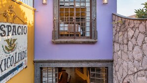 A two-story building with a balcony, a sign reading "SPACIO," and a stone wall. - Casa Esperanza, 2BR Designer Charm + Rooftop Views (San Miguel de Allende)