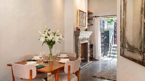 A dining area with a wooden table, chairs, a vase of flowers, and a fireplace. - Casa Esperanza, 2BR Designer Charm + Rooftop Views (San Miguel de Allende)