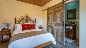 A bedroom with a bed, a nightstand, a lamp, a wooden wardrobe, and a sliding door. - Casa Esperanza, 2BR Designer Charm + Rooftop Views (San Miguel de Allende)