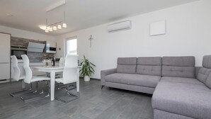 Un espace de vie moderne comprenant un coin repas, un canapé gris et une plante en pot.