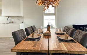 Un coin repas avec une table en bois, des chaises rembourrées et un lustre.