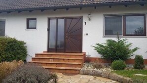 A house with a white exterior, a brown door, and a stone pathway leading to the entrance.