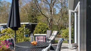 An outdoor patio area with a round table, chairs, and a black umbrella. - Cozy home in Græsted with sauna (Græsted)
