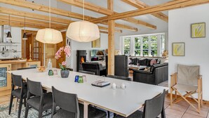 A spacious dining area with a long table, black chairs, and hanging light fixtures. - Cozy home in Græsted with sauna (Græsted)