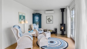 A cozy living room with wicker furniture, a blue rug, and a black wood stove.