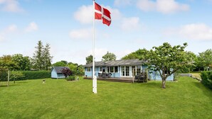 A house with a flagpole, a porch, and a garden.