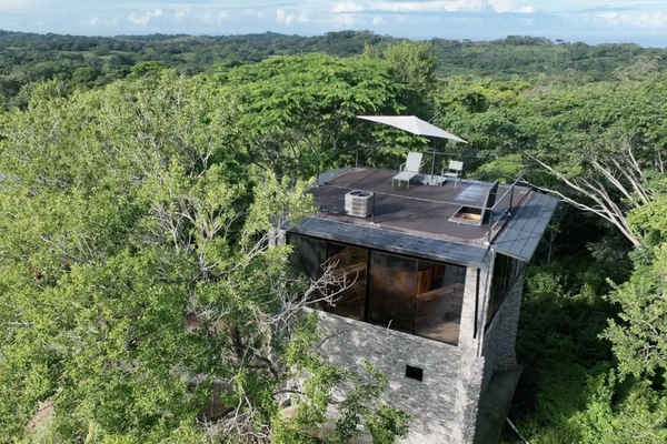 Aerial shot of the tower with the ocean in the background, main house on left