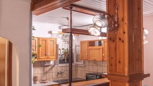 Et køkken med træskabe, en central ø og en hængende lampe.