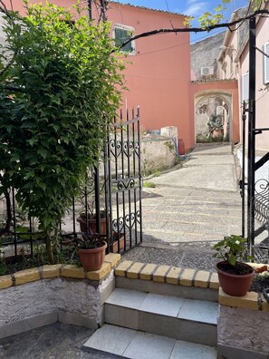 Stroll through the charming entrance, flanked by lush greenery and a beautifully designed gate.