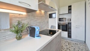 Une cuisine moderne équipée d’un four encastré, d’un four à micro-ondes et d’une machine à café posée sur le plan de travail.