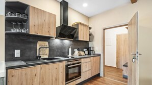 Une cuisine moderne avec des meubles en bois, un plan de travail noir et une hotte en acier inoxydable.