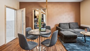 Un salon moderne avec une table ronde, quatre chaises grises, un canapé gris et un tapis bleu.