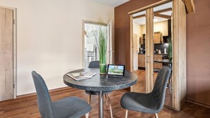 Un coin repas avec une table ronde, deux chaises, un ordinateur portable et un vase avec des plantes.