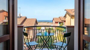 A balcony with a table and chairs, overlooking a residential area and the sea. - 2 bedroom gorgeous apartment in San Costanzo (San Costanzo)