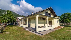 Ein zweigeschossiges Haus mit Satteldach, überdachter Veranda und kleinem Vorgarten.