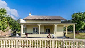 Ein zweistöckiges Haus mit Balkon, Ziegeldach und einem umzäunten Garten.