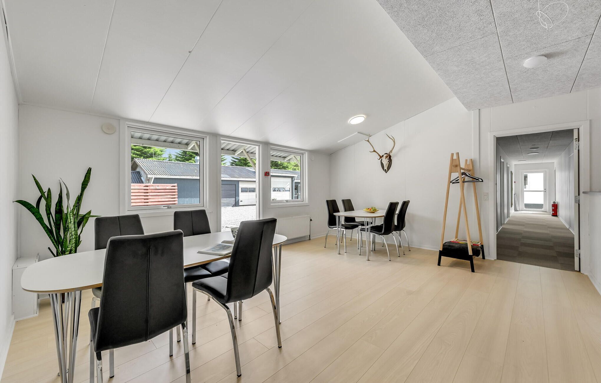 A modern dining area with a white table and black chairs, large windows, and a ceiling with a textured pattern.