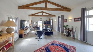 A spacious living area with a high ceiling, a large rug, and a dining area visible in the background. - Amazing home in Murviel Les Montpellie (Murviel Les Montpellie)