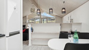 A modern kitchen with white cabinetry, a dining area with a round table, and pendant lighting.