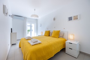 A hotel room with a large bed, a bedside table with a lamp, a wardrobe, and a window with curtains.