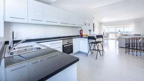 A modern kitchen with white cabinets, a black countertop, and a built-in oven. - Casa do Limoeiro 54 LBC by CoolHouses (Praia da Luz)