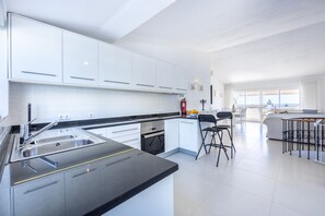 A modern kitchen with white cabinets, a black countertop, and a built-in oven.
