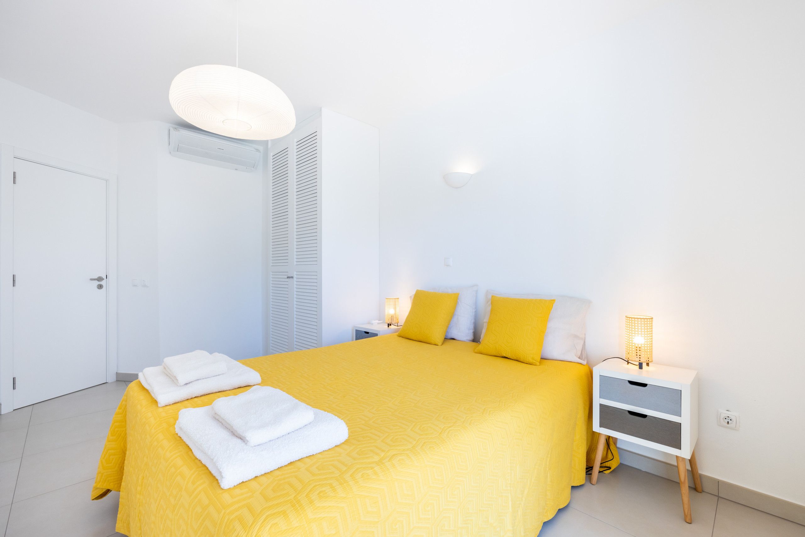 Et hotelværelse med seng, sengeborde, lampe og dør.