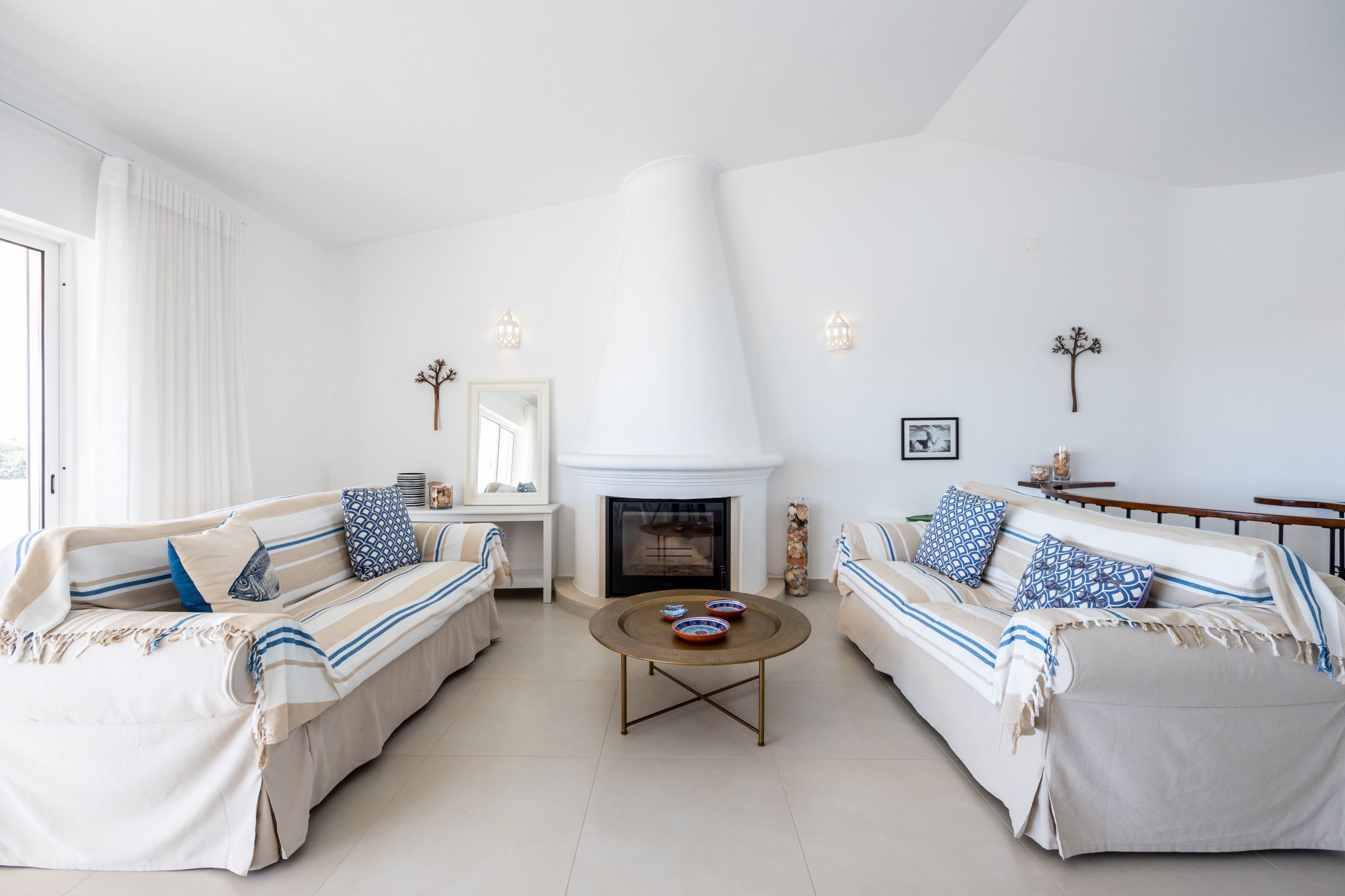A living room with two sofas, a coffee table, a fireplace, and decorative wall sconces.