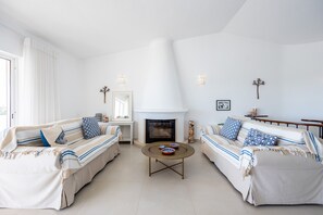 Ein Wohnzimmer mit zwei Sofas, einem Couchtisch, einem Kamin und dekorativen Wandleuchten.