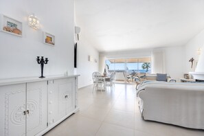 Une chambre d’hôtel avec un balcon, un lit, un coin repas et une armoire blanche aux portes décoratives.