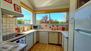A compact kitchen with a microwave, sink, and a window overlooking greenery. - Maison côte sauvage. classement 3* (Quiberon)