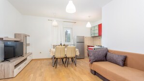 A compact living space with a TV, dining table, chairs, a sofa, and a kitchenette. - 2 bedroom nice apartment in Cernik (Cernik)