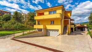 A two-story yellow building with a balcony, a paved entrance, and a view of the surrounding area. - 2 bedroom nice apartment in Cernik (Cernik)