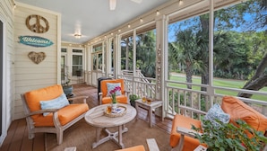 A covered porch with wooden furniture, a ceiling fan, and a view of the outdoors. - 23 Ocean Green-  Comm. Pool, 4 Bed, Golf Views, Walk to Beach!! (Kiawah Island)