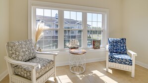 A room with two chairs, a small table, and a large window with a view of houses. - Murrells Inlet Golf Resort Condo: 1 Mile to Beach! (Murrells Inlet)