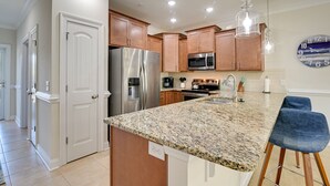 A modern kitchen with granite countertops, stainless steel appliances, wooden cabinets, and pendant lighting. - Murrells Inlet Golf Resort Condo: 1 Mile to Beach! (Murrells Inlet)