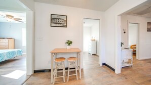 A spacious room with a wooden table and two chairs, a ceiling fan, a framed picture on the wall, and a view into another room. - Charming Cottage w/ Yard < 1 Mi to Lake Erie! (Geneva)