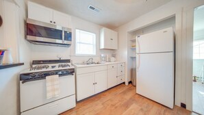 A kitchen with white cabinets, a stainless steel stove, a microwave, and a refrigerator. - Charming Cottage w/ Yard < 1 Mi to Lake Erie! (Geneva)