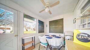 A room with a ceiling fan, a table with a white tablecloth and blue placemats, a chair, and a shelf. - Charming Cottage w/ Yard < 1 Mi to Lake Erie! (Geneva)