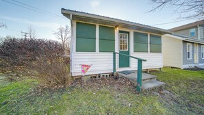 A single-story house with a green door and windows, a small front porch, and a grassy yard. - Charming Cottage w/ Yard < 1 Mi to Lake Erie! (Geneva)