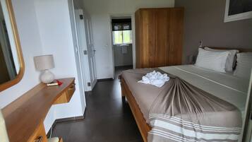 A bedroom with a bed, a wooden wardrobe, a bedside table with a lamp, and a mirror.